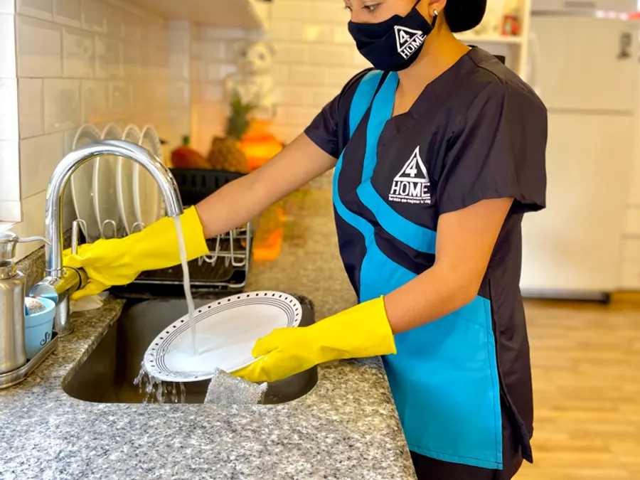 Trabajadora de 4HOME limpiando una cocina con guantes